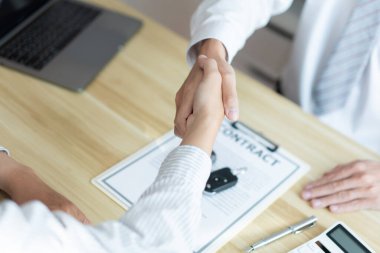 Sigorta konsepti araba komisyoncusu sözleşmeyi bitirdikten sonra müşterisiyle el sıkışıyor..