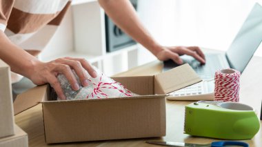Çevrimiçi alışveriş kavramı ürün tedarikçisi göndermeden önce bilgisayardaki detayları ve paketin içindeki gerçek ürünü kontrol eder..