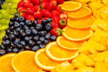 Taze meyve kavramı, portakallı kivi düzenlemesi ve arka plan olarak çeşitli meyveler..