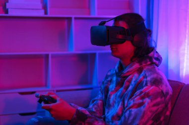 Metaverse teknoloji konsepti, insan sanal dünyada oyun oynamak için VR gözlük takar ve joystick kullanır.