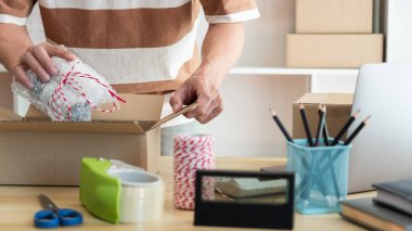 Çevrimiçi alışveriş konsepti. Satıcı ürününü paketleyip pakete koyuyor..