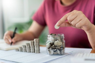 Tasarruf konsepti. Kadın şişeye bozuk para koyar ve paranın miktarını not eder..