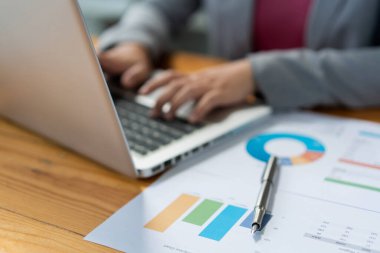 İş analisti kadın memurun bilgisayar laptopunda finansal bilgiler yazdığını düşünüyor..