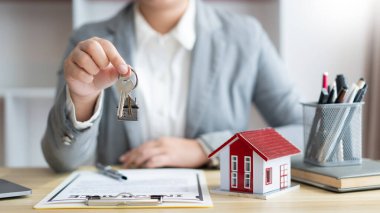 Sigorta konsepti. Emlak temsilcisi kontratı imzaladıktan sonra ev anahtarını müşterisine veriyor..