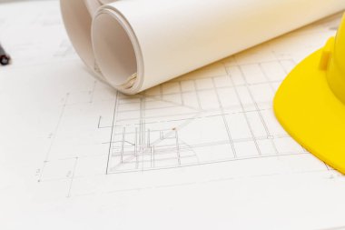 Mimari konseptin modeli, çizim araçları ve güvenlik kaskıyla plan üzerine çizim yapan mühendis.