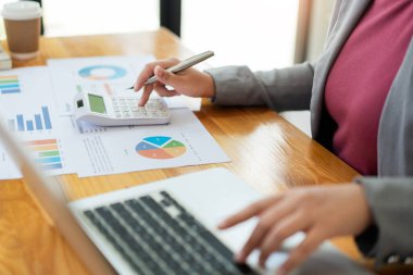 İş analisti, hesap makinesi kullanarak bilgisayardaki verilerin doğruluğunu kontrol eder..