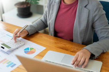 İş analisti, hesap makinesi kullanarak bilgisayardaki verilerin doğruluğunu kontrol eder..