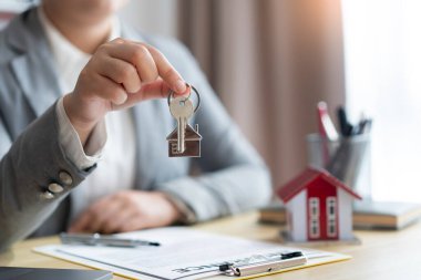 Sigorta konsepti. Emlak temsilcisi kontratı imzaladıktan sonra ev anahtarını müşterisine veriyor..