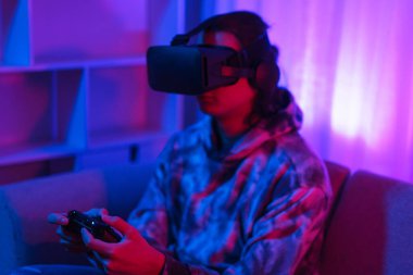 Metaverse teknoloji konsepti, insan sanal dünyada oyun oynamak için VR gözlük takar ve joystick kullanır.
