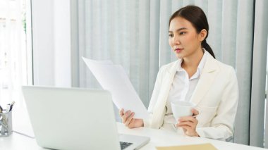 Kendine güvenen kadın konsepti, kahve içen ve belgelerde finansal verileri okuyan iş kadını.