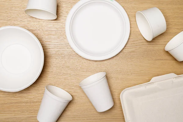 Çevre dostu kavram, yiyecek kabı seti ve tahtadan arka planda biyolojik olarak çözünebilen kağıt bardak..