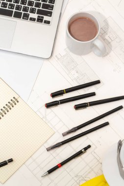 Mimari konseptin modeli, güvenlik kaskıyla plan çizimi üzerine çizim aracı ve kahve.