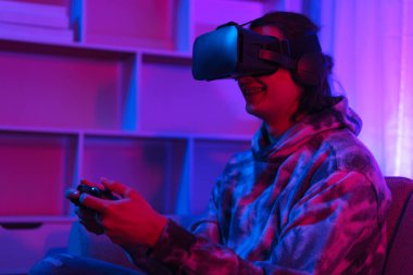 Metaverse teknoloji konsepti, insan sanal dünyada oyun oynamak için VR gözlük takar ve joystick kullanır.