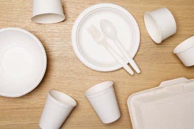 Çevre dostu kavram, yiyecek kabı seti ve tahtadan arka planda biyolojik olarak çözünebilen kağıt bardak..