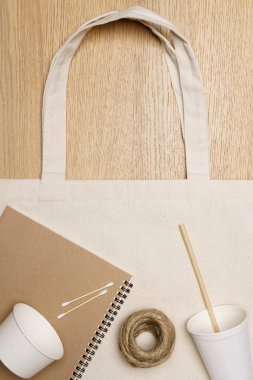 Çevre dostu kavram, defter kâğıdı bardaklı eko çanta ve ahşap arka planda jüt ip..