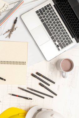 Mimari konseptin modeli, güvenlik kaskıyla plan çizimi üzerine çizim aracı ve kahve.