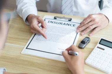 Sigorta konsepti. Erkek satıcı müşterisine araba satın alma sözleşmesini imzalamasını öneriyor..