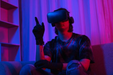 Metaverse teknoloji konsepti, insan oyun oynarken jest yaparken VR gözlük ve eldiven takar.