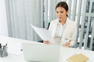 Kendine güvenen kadın konsepti, kahve içen ve belgelerde finansal verileri okuyan iş kadını.