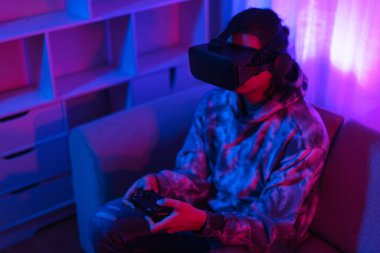 Metaverse teknoloji konsepti, insan sanal dünyada oyun oynamak için VR gözlük takar ve joystick kullanır.
