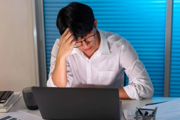 過労の概念男は机の上に座って眼鏡を外し 仕事をしながら頭を抱えていた — ストック写真