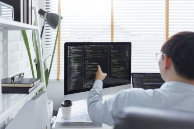 Yazılım geliştirme kavramı, belge ve bilgisayar ekranında veri kodlarını kontrol eden erkek programcı.