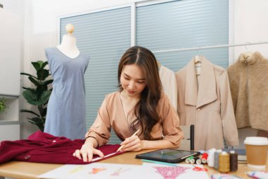 Moda tasarımı konsepti, Asyalı kadın terzi yeni elbise dikmek için kumaş ölçüsü kullanıyor..