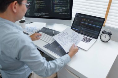 Yazılım geliştirme kavramı, Erkek programcı bilgisayardaki programlama sırasında belge üzerindeki verileri okur.
