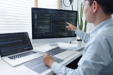 Yazılım geliştirme kavramı, belge ve bilgisayar ekranında veri kodlarını kontrol eden erkek programcı.