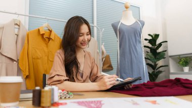 Moda tasarımı konsepti, Asyalı kadın moda tasarımcısı tablete yeni kıyafet koleksiyonu çiziyor.