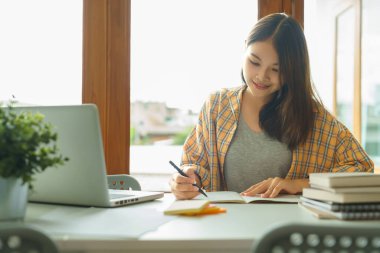 Eğitim ve okur yazarlık kavramı, üniversiteli kız dizüstü bilgisayar kullanıyor ve kütüphanede ödev yapıyor..