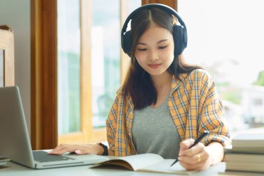 Education and literacy concept, College student girl is listening lecture online and taking notes.