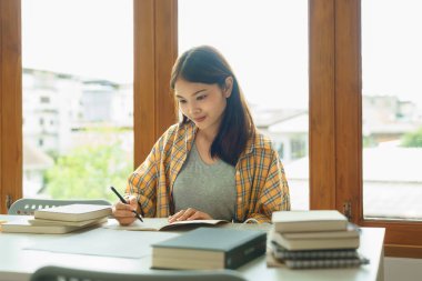 Eğitim ve okur yazarlık kavramı, kolej öğrencisi kız ders kâğıtlarını okur ve deftere not alır..