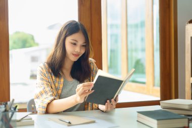 Education and literacy concept, College student girl is reading textbook in college library.