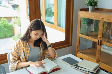 Eğitim ve okur yazarlık kavramı, üniversite öğrencisi kız kütüphanede kitap okurken kafası karışıyor.