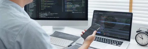Software development concept, Male programmer check website programming on smartphone and computer.