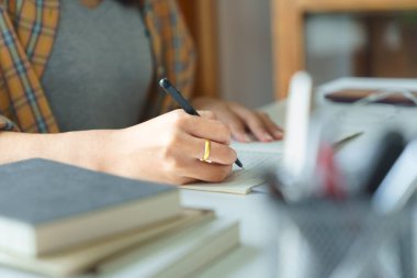 Eğitim ve okur yazarlık kavramı, kolej öğrencisi kız ders kâğıtlarını okur ve deftere not alır..