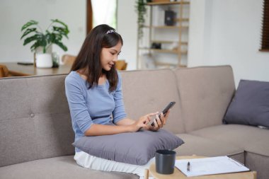 Work from home concept, Business women use smartphone to search data while working remotely at home.