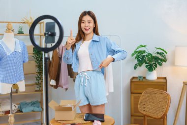 Online shopping concept, Young Asian women trying on shirt and recommend clothes in streaming video.