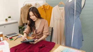 Moda tasarımı konsepti, Asyalı kadın moda tasarımcısı tablete yeni kıyafet koleksiyonu çiziyor.