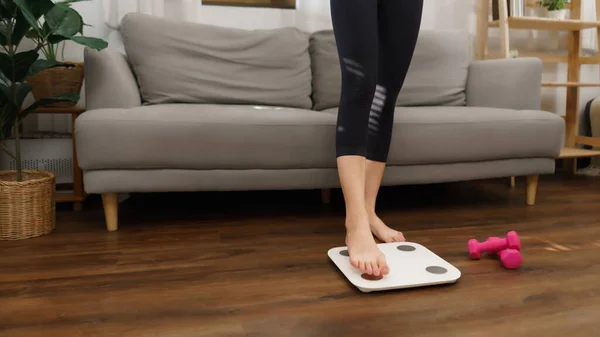 Healthy and weight loss concept, Young Asian woman stepping on weighing scales after weight control.