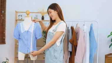 Fashion blogger concept, Asian women measure length of shirt to present and sell in streaming video.
