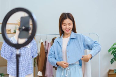 Fashion blogger concept, Young Asian women trying on shirt and present detail in streaming video.