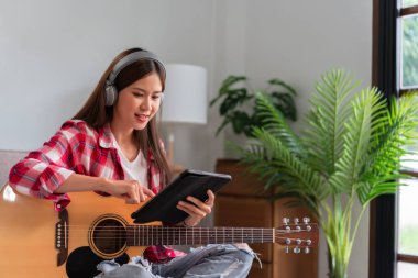 Concept of relaxation with music, Young asian woman wearing earphone and learning music on tablet.