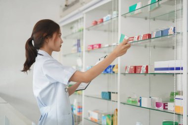 Medicine and health concept, Female pharmacist hold medicine box to checklist in paper at drugstore.