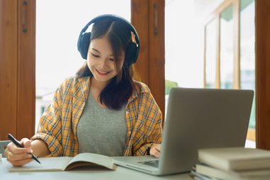 Education and literacy concept, College student girl is listening lecture online and taking notes.