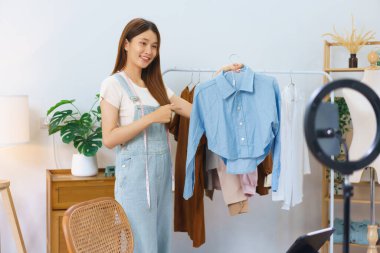 Moda blogcusu konsepti. Genç Asyalı kadınlar tişört satıyorlar ve video yayınında sunuyorlar..