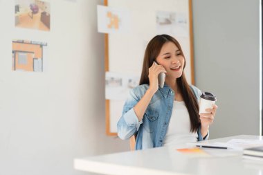 Tasarım geliştirme konsepti, akıllı telefondan konuşan kadın mimar taslak çiziminden sonra dinleniyor.