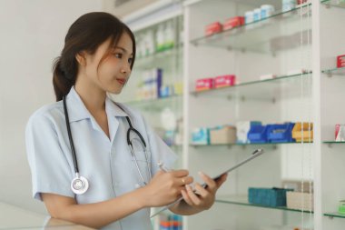 Medicine and health concept, Female pharmacist checking medicine on shelves to checklist in paper.