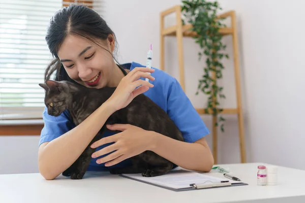 ペットケアの概念 女性の獣医は獣医クリニックで猫を注射するための予防接種を準備します — ストック写真
